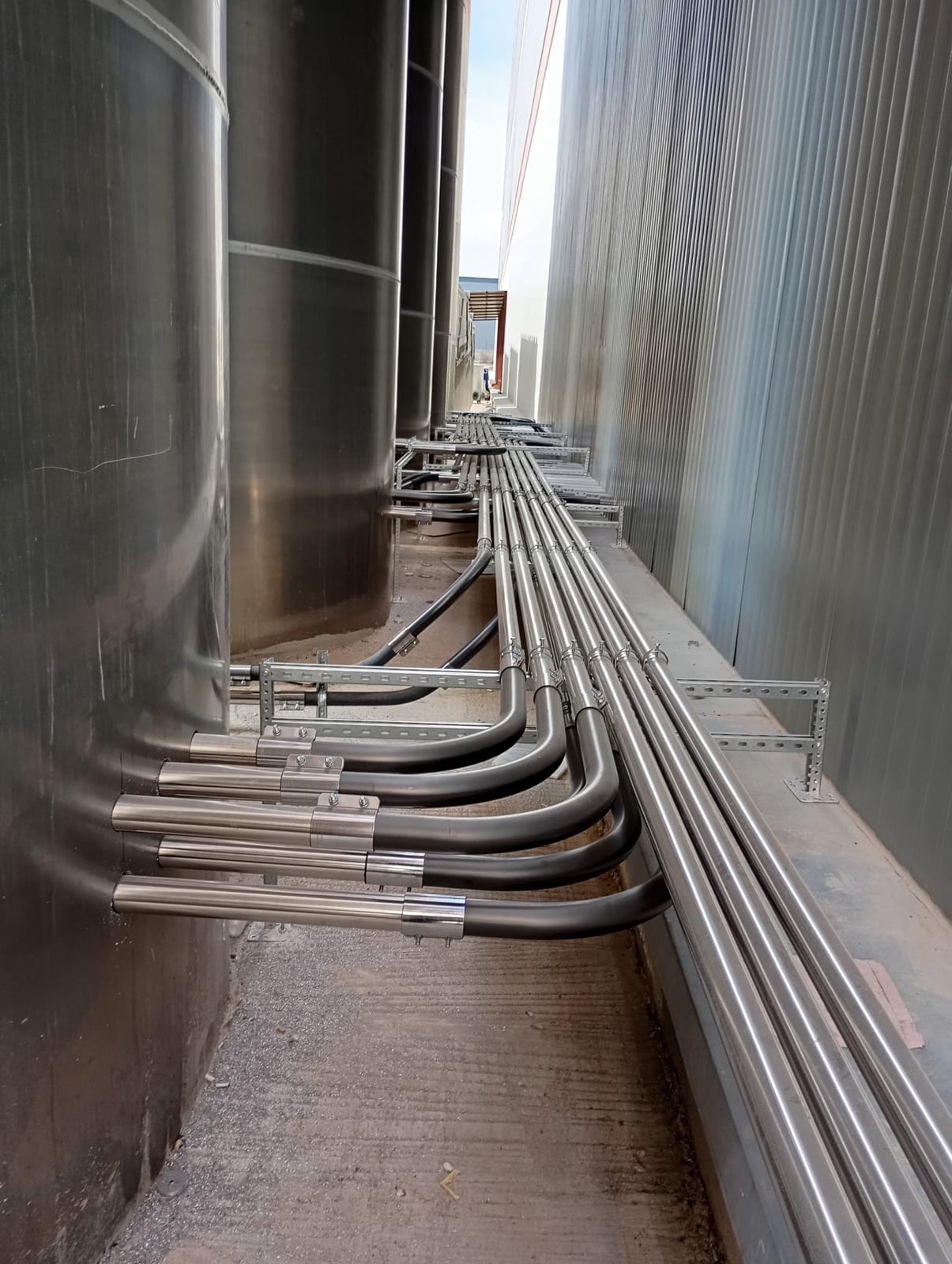 Stainless raw-material transport lines running from the silos to the production lines